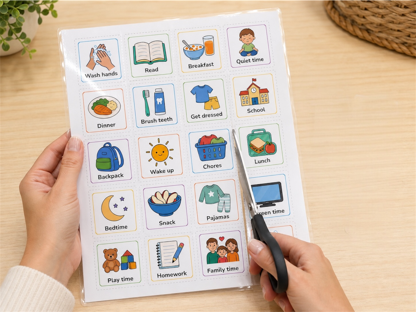 Hands cutting laminated visual schedule tiles from a printed sheet